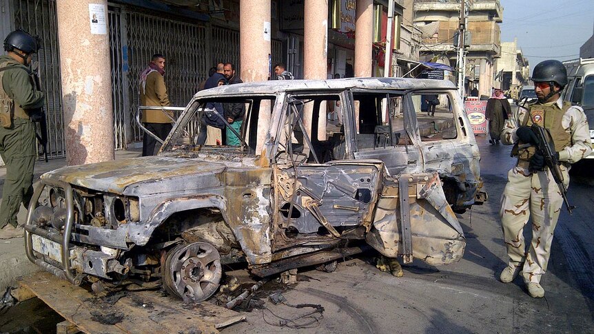 A soldier stands guard near a burnt vehicle after a bomb attack in Alawi district, central Baghdad on December 22, 2011.