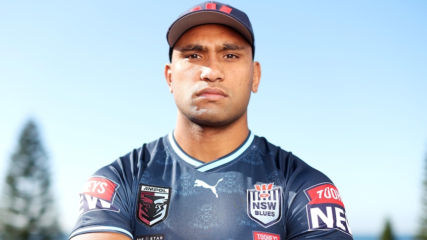 A man stares at the camera while wearing a rugby league jersey