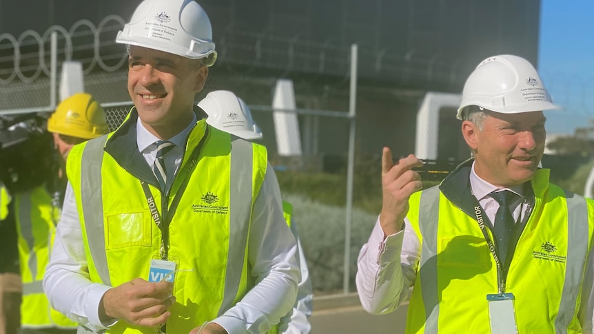 Two men wearing yellow hi-viz vests and white hard hats