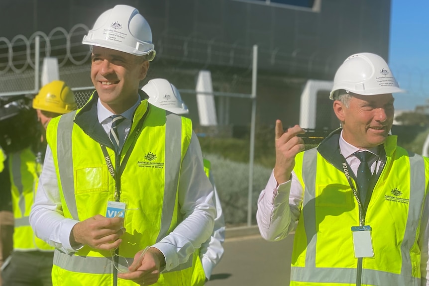 Two men wearing yellow hi-viz vests and white hard hats