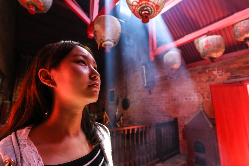 First time visitor to the Bendigo Joss House Temple, tertiary student Xiaoyu Liu standing beneath lanterns.