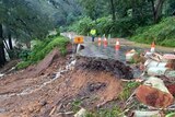a road has a large section missing after it was washed down an embankment