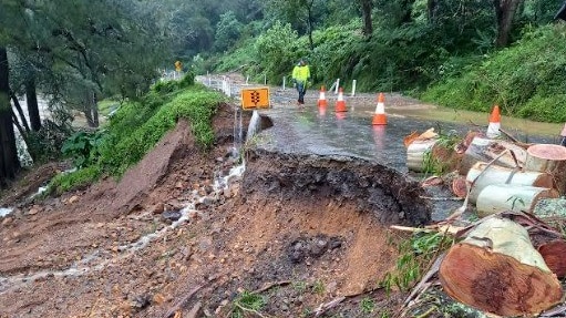 a road has a large section missing after it was washed down an embankment