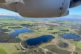 A plane flies over water reservoirs.