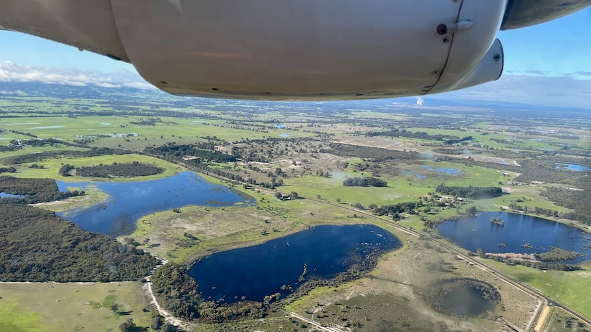 A plane flies over water reservoirs.