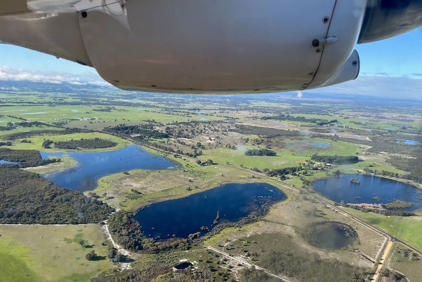 A plane flies over water reservoirs.