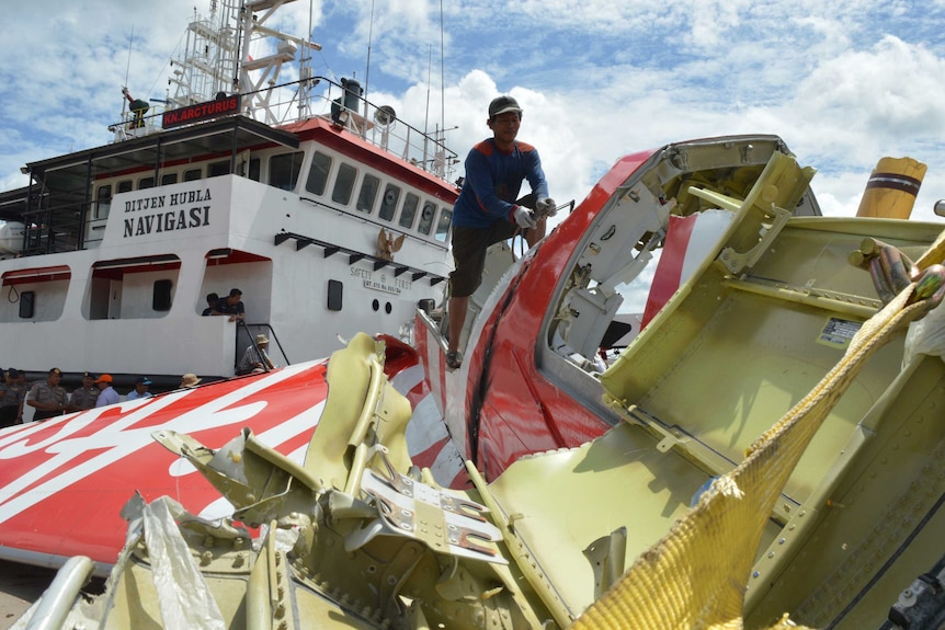 An Indonesian worker cuts the tail of the AirAsia flight after debris from the crash was retrieved.