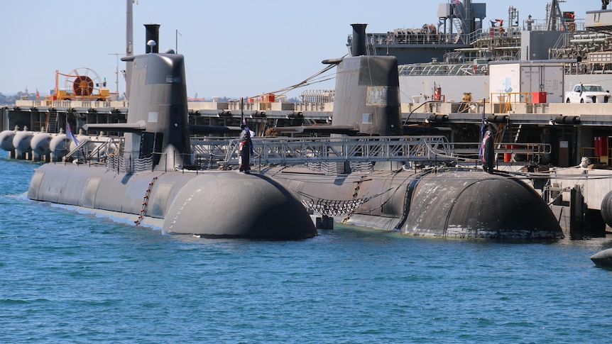 Submarines sit half submerged at a dock in the ocean