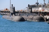 Submarines sit half submerged at a dock in the ocean