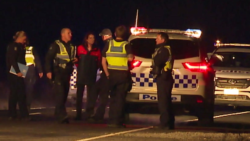 Investigators standing in front of police cars at the scene of the hit and run.