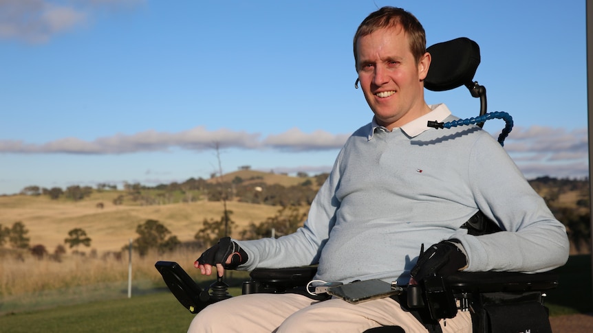 A man sits in a wheelchair in hill surrounds