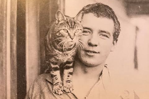 A sepia photograph of a sailor with a tabby cat on his shoulder