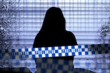 The silhouette of a woman as she stares out the window while sitting on a bed