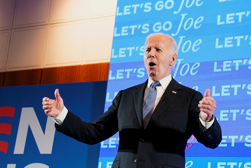 Joe Biden gives a double thumbs up as he speaks to supporters in front of a "let's go Joe" sign.