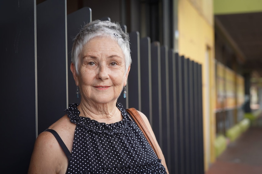 Woman with short grey hair smiles at camera on street