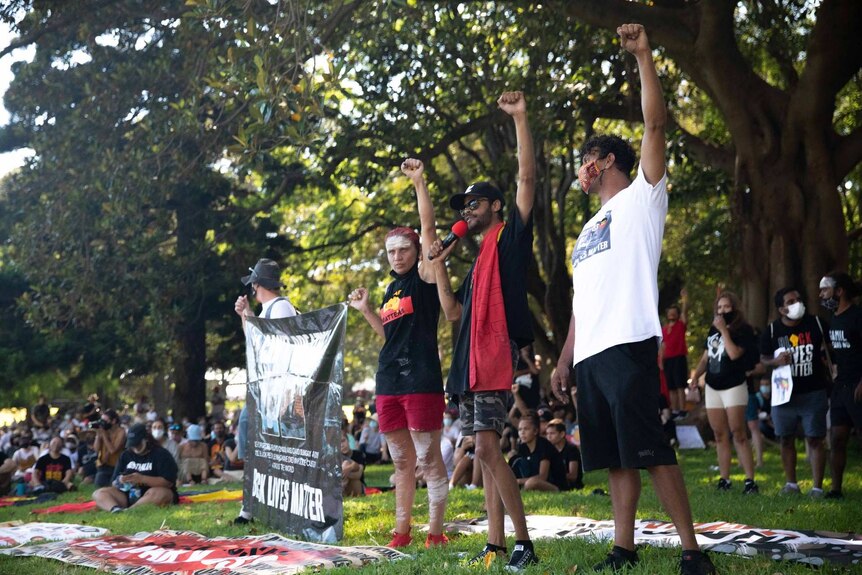 four people standing in a park with their fists raised in the air