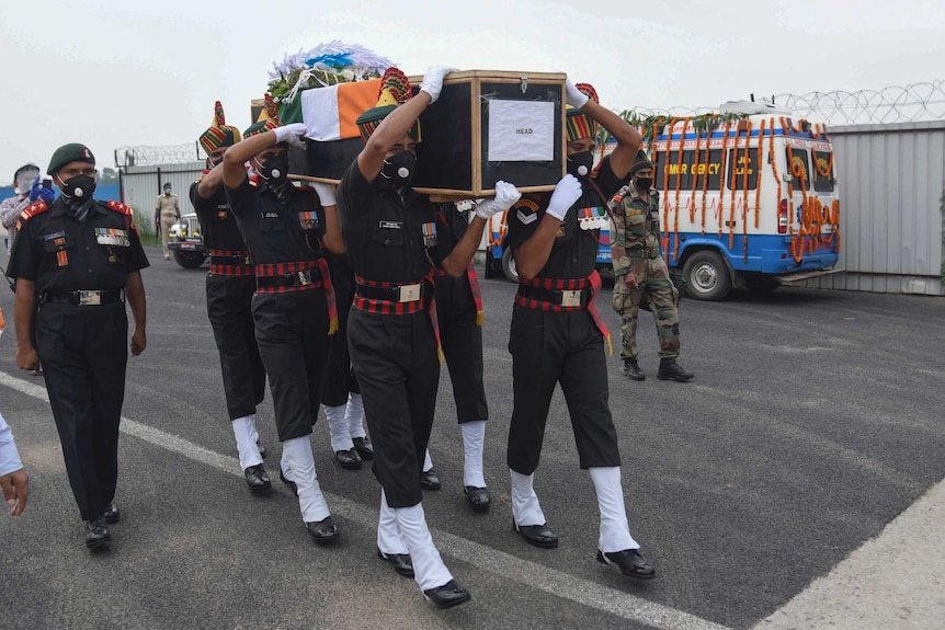 Indian army soldiers dressed in military uniform carry the coffin of their colleague.