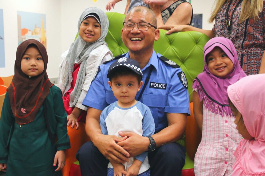 Police officer sitting on green chair with children