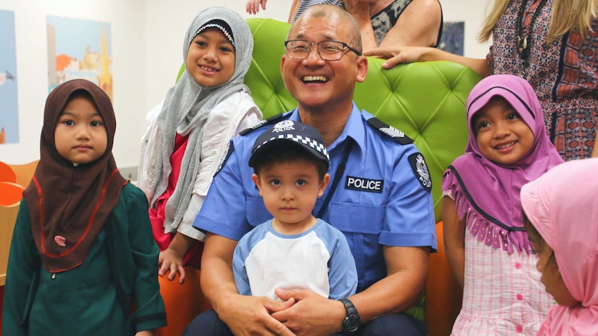 Police officer sitting on green chair with children