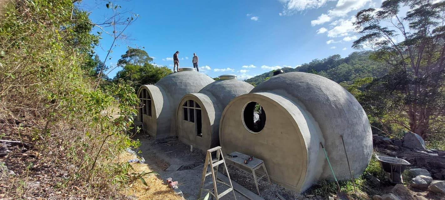Cath Wild and friend stand atop Aircrete Dome Elysian Falls partway through construction.