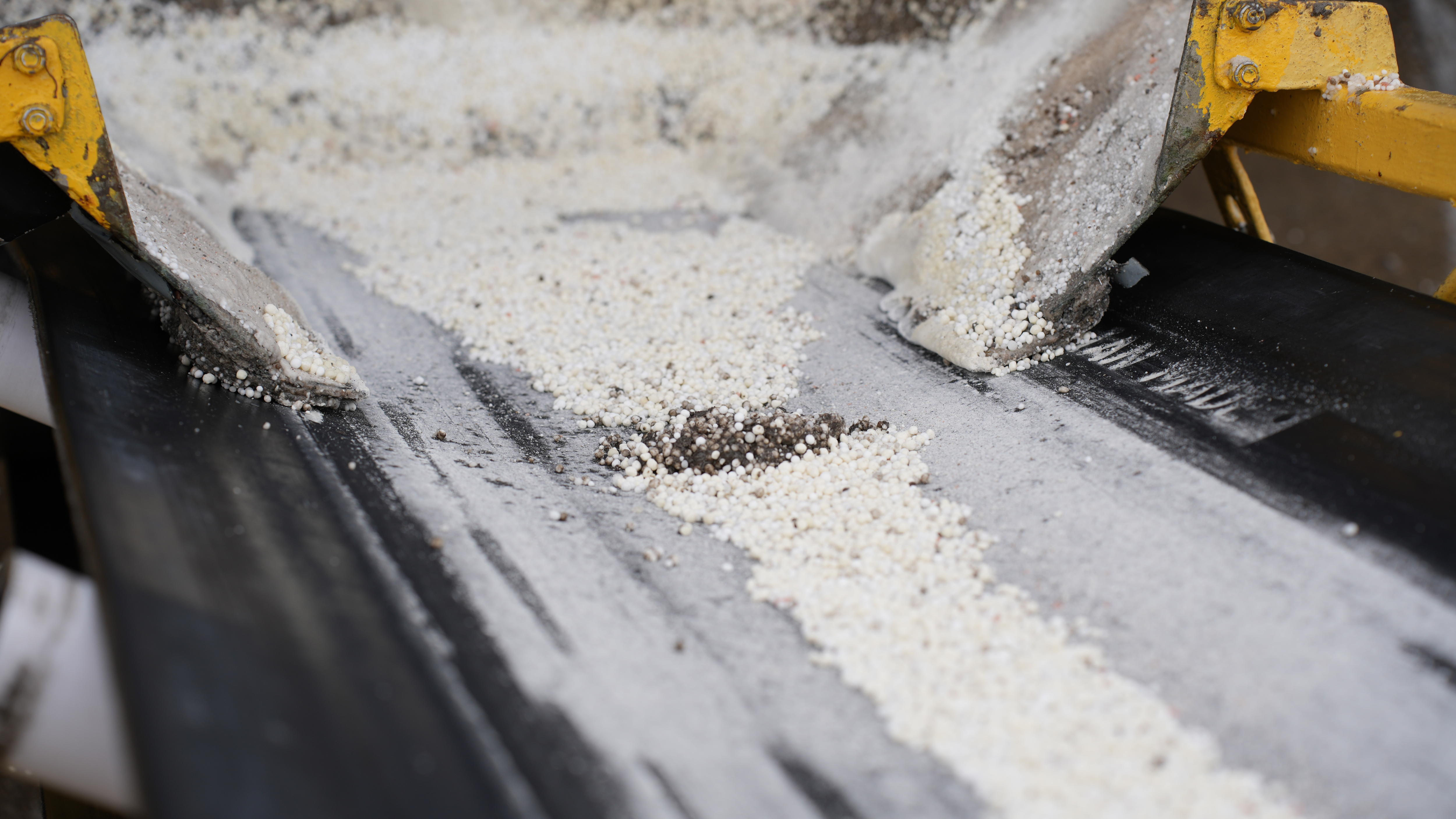 A white fertiliser mix made up of urea and sulphate of ammonia on a conveyor belt