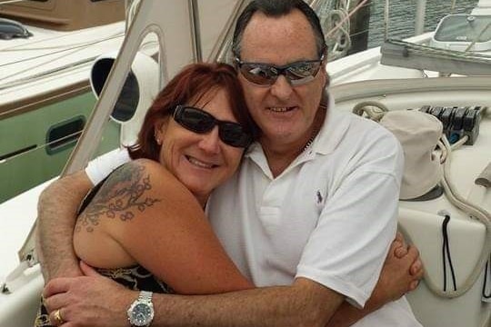 A woman and a man embrace while sitting on a yacht.