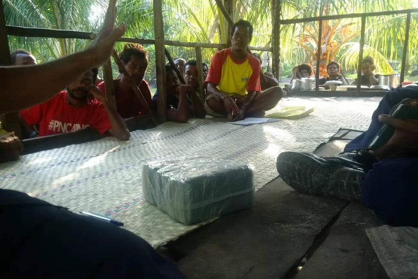 People sitting around a parcel containing drug.