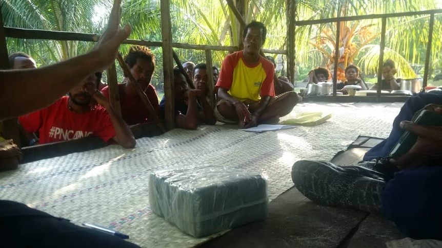 People sitting around a parcel containing what is believed to be drugs.