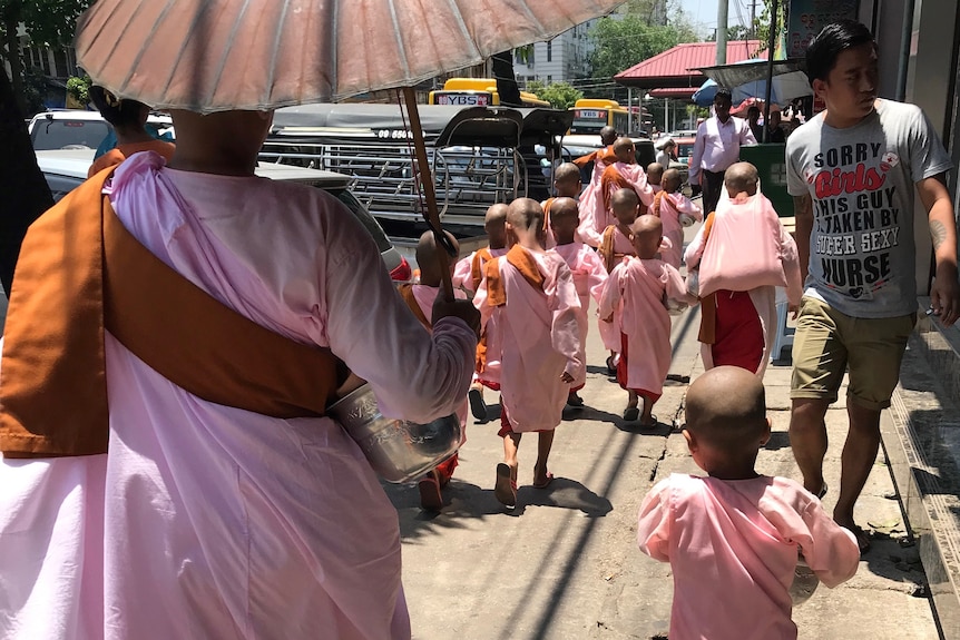 Small children dressed in pink robes becoming nuns.