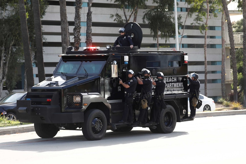 A group of police man riding an armoured car