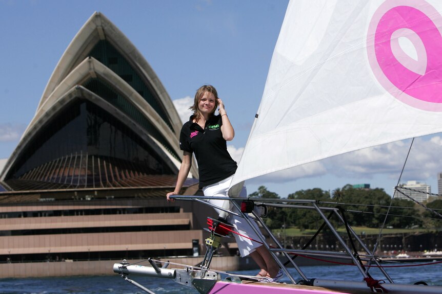 Jessica Watson sits on pink sail boat, sydney opera house in background