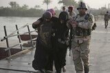 An Iraqi soldier help displaced women on the outskirts of Baghdad