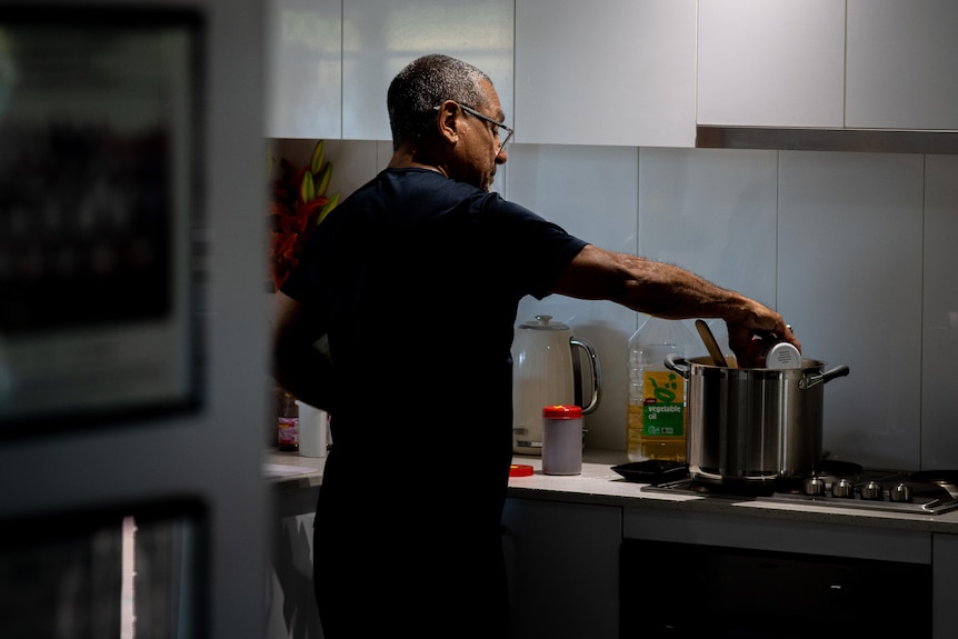 a man stands over a pot that's cooking on the stove top and adds ingredients to the mix.