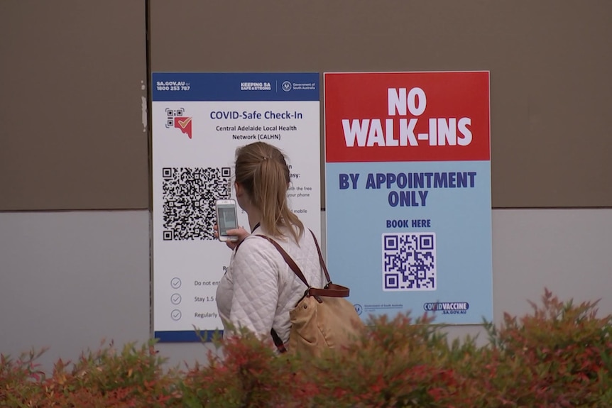 A woman checks in on a QR code on a large sign