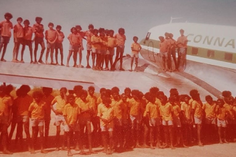About 50 children standing on aeroplane