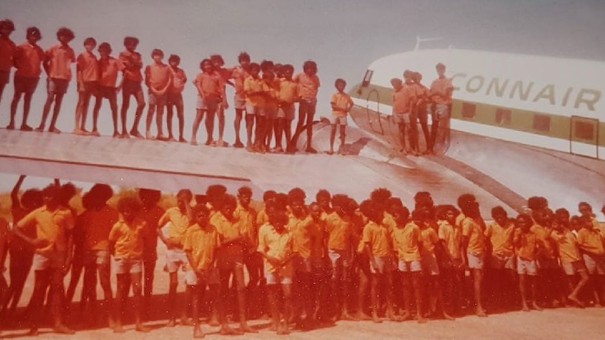 About 50 children standing on aeroplane