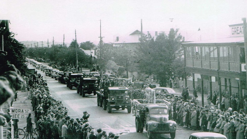 A black and white photograph of the main street in Wagga Wagga with people lining both sides to watch a funeral procession