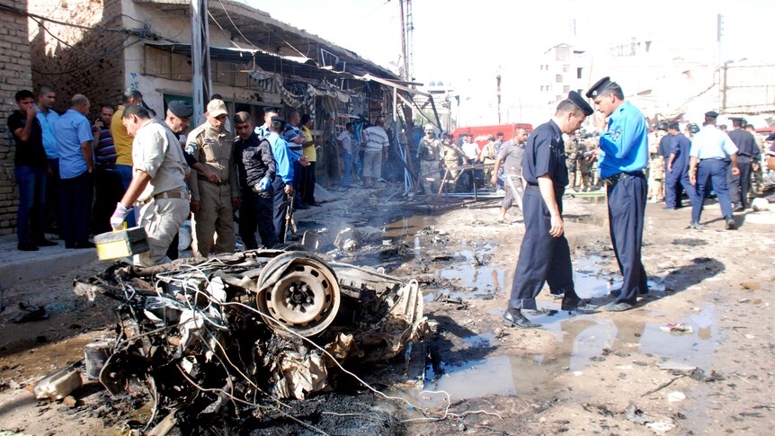 Officials inspect the remains of a vehicle used in a bomb attack in Kut in August 2011.