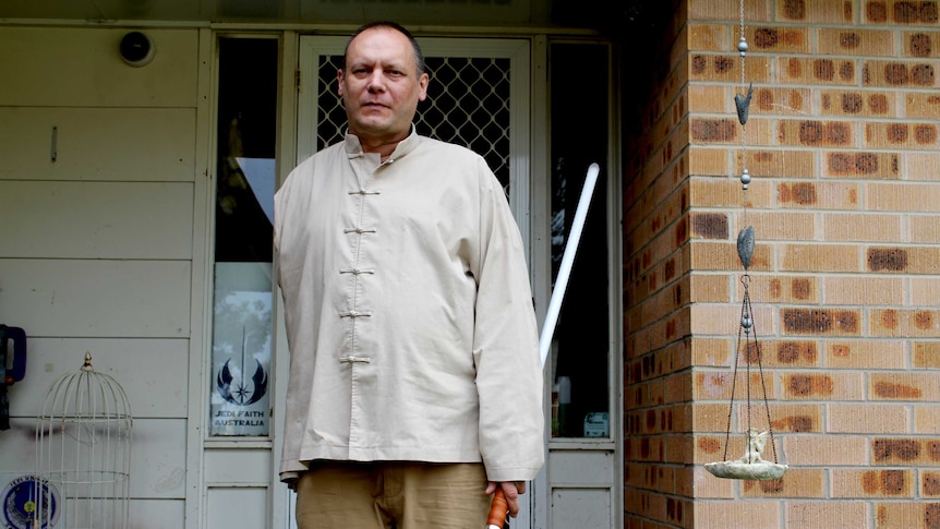 Jedi leader Peter Lee holds a lightsaber outside his home