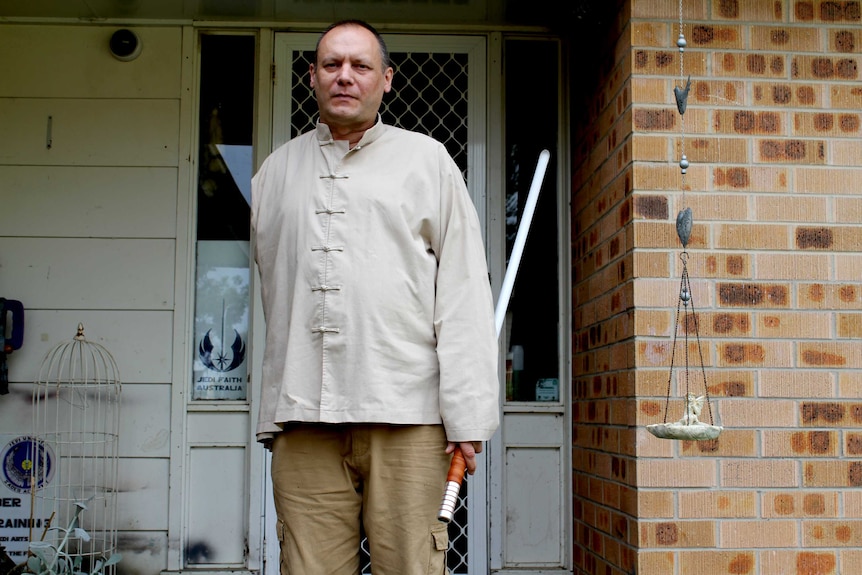 Jedi leader Peter Lee holds a lightsaber outside his home