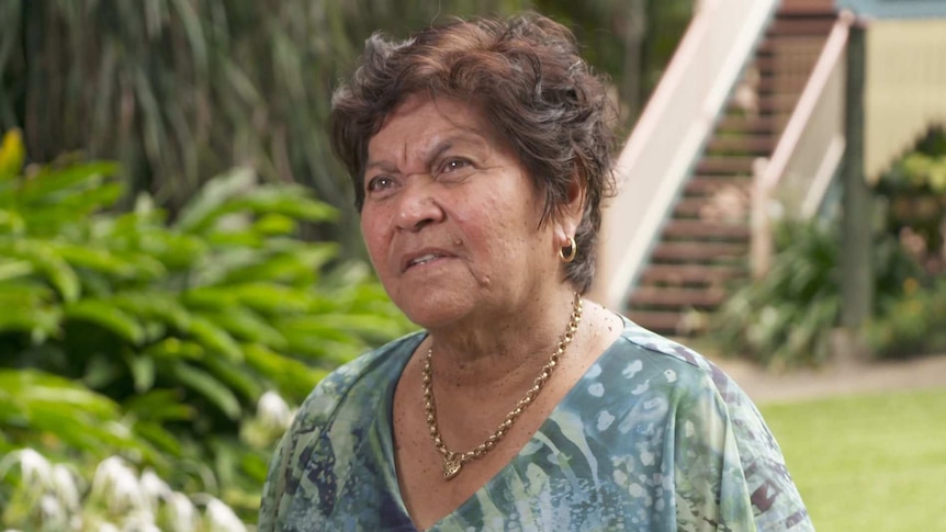 An Indigenous woman looking at an interviewer wearing a green printed shirt.