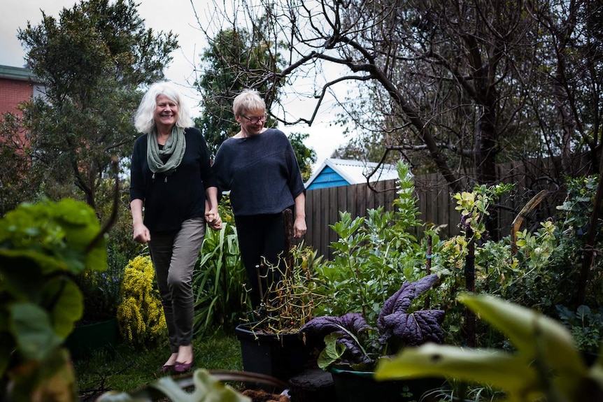 Penny Whetton and Janet Rice hold hands as they wander around their garden.