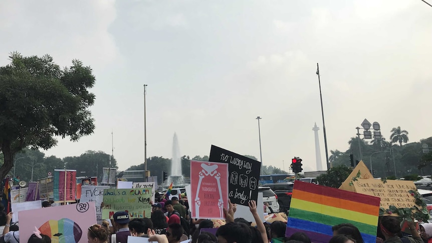 Campaigners hold signs including a rainbow flag during a protest march for LGBT and women's rights.