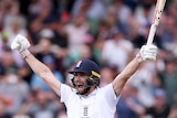 Chris Woakes holds his arms in the air and yells in delight