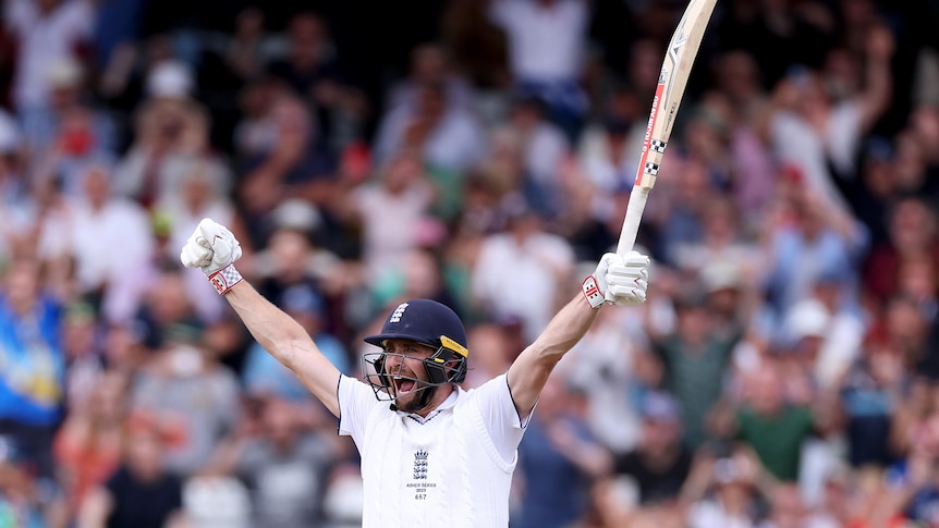 Chris Woakes holds his arms in the air and yells in delight