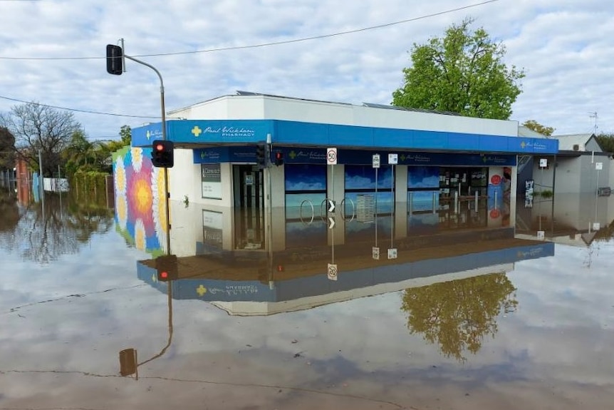 The exterior of the pharmacy which has water up to the windows. It is reflected perfectly in the water.