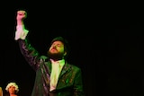 A man holds his fist in the air on stage