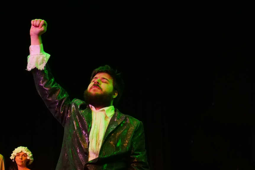 A man holds his fist in the air on stage