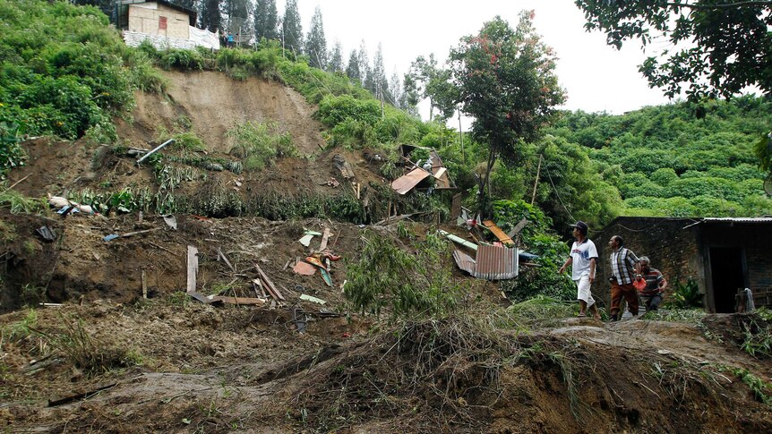 Indonesian villagers walk the area after heavy rain swept and killed nine people in Karo