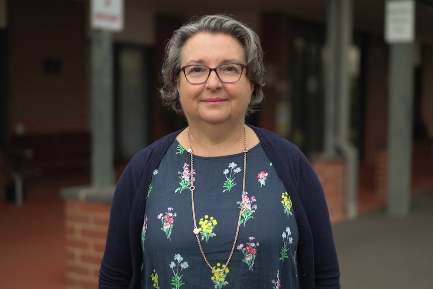 Woman wearing a blue top with flowers and a navy cardigan.